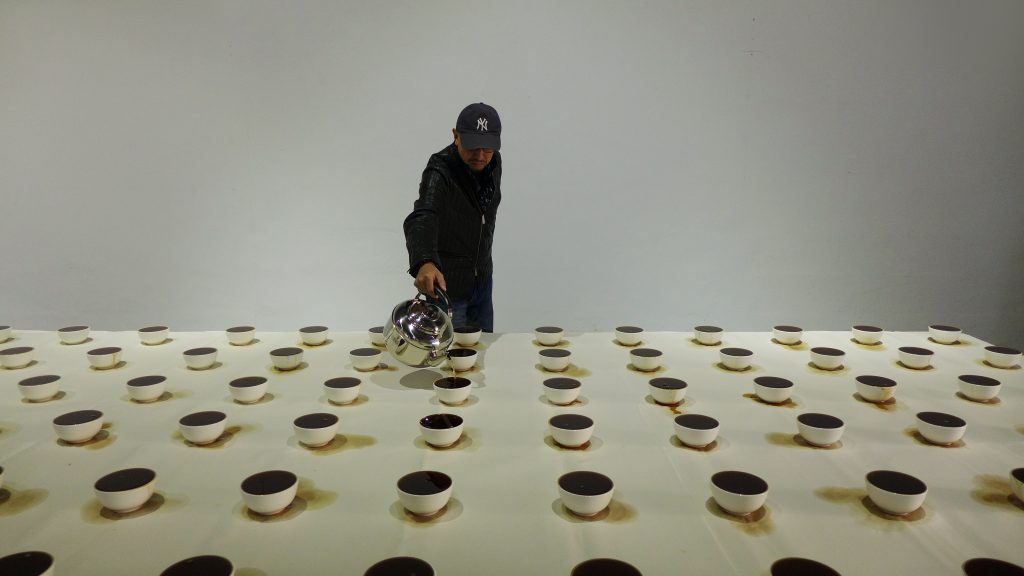 Performance-Art-and-Installation-Art-by-Zhang-YuOn-a-piece-of-xuan-paper-1.5x3.5mthe-artist-has-placed-rows-of-porcelain-bowls-periodically-filling-them-with-pu’er-tea